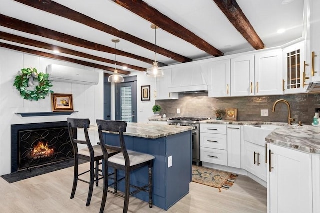 38 S St, Grafton, MA 01519 - kitchen featuring high end stove, a wall mounted air conditioner, a kitchen breakfast bar, premium range hood, and light wood finished floors