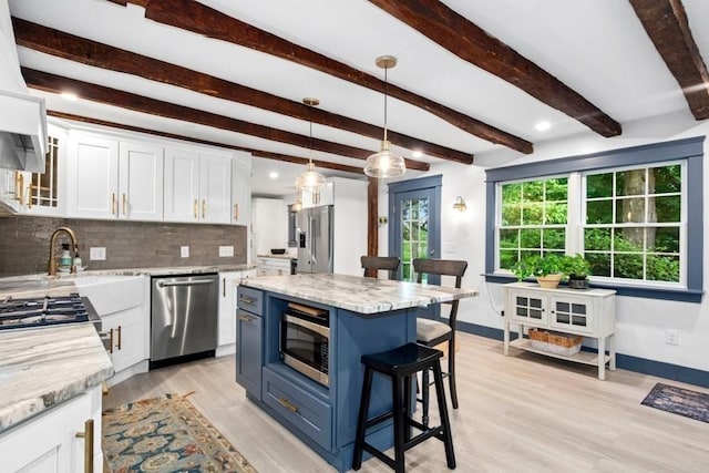 38 S St, Grafton, MA 01519 - kitchen with appliances with stainless steel finishes, blue cabinets, a breakfast bar area, white cabinets, and beamed ceiling