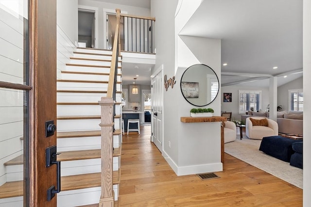 foyer entrance featuring a towering ceiling and light hardwood / wood-style flooring