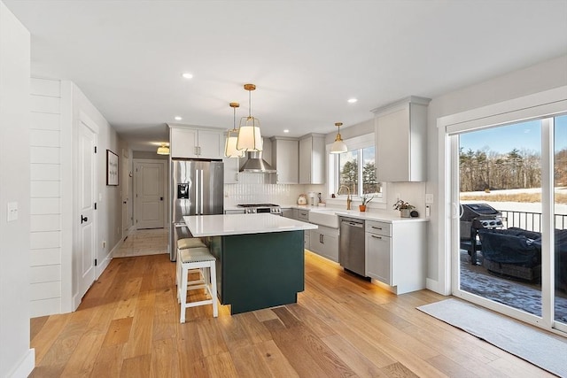 kitchen featuring a kitchen bar, a center island, light wood-type flooring, appliances with stainless steel finishes, and pendant lighting