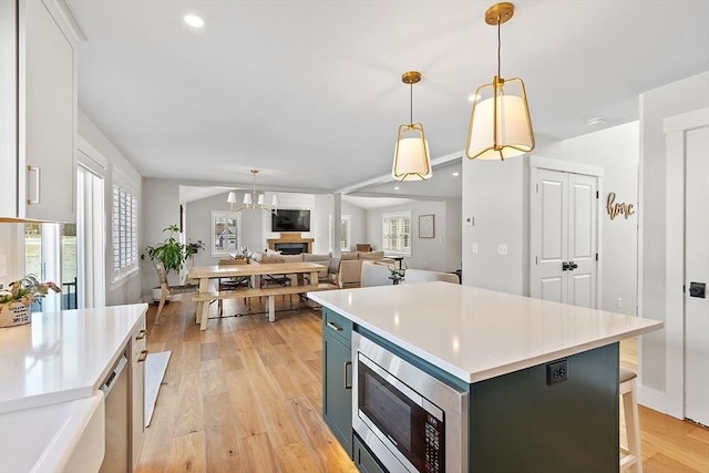 kitchen featuring stainless steel appliances, white cabinetry, a center island, and decorative light fixtures