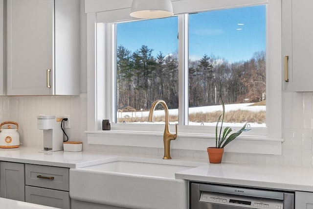 kitchen with tasteful backsplash, sink, gray cabinets, and stainless steel dishwasher