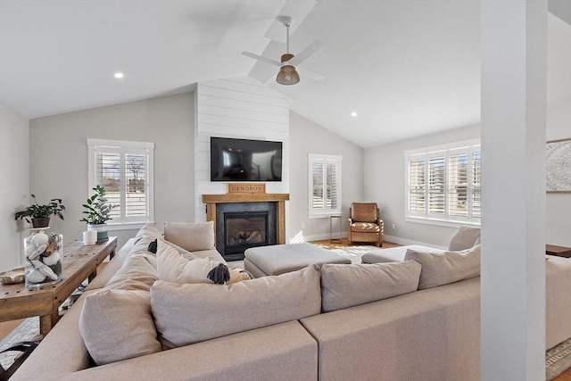 living room featuring lofted ceiling, a large fireplace, and ceiling fan