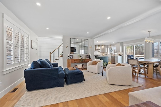 living room with light hardwood / wood-style floors and a notable chandelier