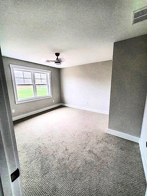 carpeted empty room with ceiling fan and a textured ceiling