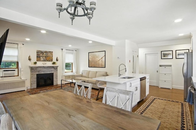 182 Winn St, Woburn, MA 01801 - dining room featuring radiator, dark wood-style flooring, recessed lighting, a fireplace with raised hearth, and a chandelier