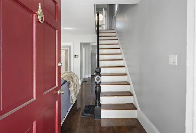 foyer featuring dark wood finished floors, stairway, and baseboards