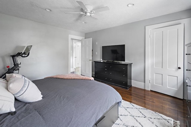 bedroom featuring wood finished floors, a ceiling fan, a textured ceiling, and baseboards