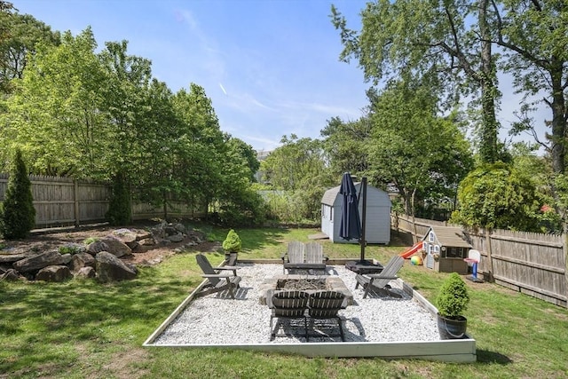 view of yard featuring a shed, a fire pit, an outbuilding, and a patio