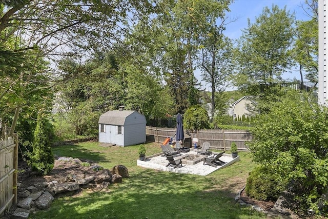 view of yard featuring a patio, an outdoor fire pit, a shed, and an outbuilding