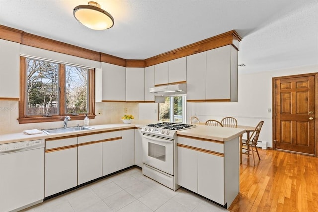 kitchen featuring white appliances, light countertops, a sink, and white cabinets