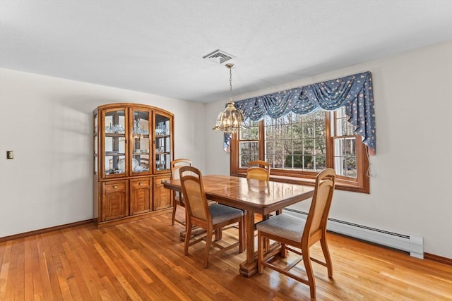 dining area featuring a baseboard heating unit, light wood finished floors, visible vents, and baseboards