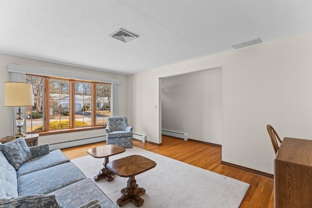 living area featuring a baseboard heating unit, visible vents, and wood finished floors