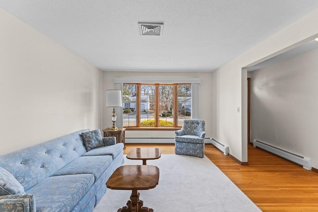 living room with a textured ceiling, a baseboard radiator, wood finished floors, and baseboards