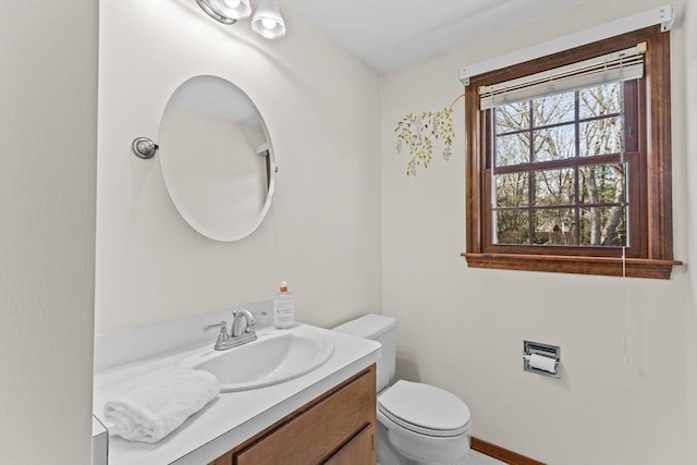 bathroom with toilet, vanity, and baseboards