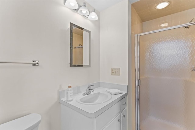 bathroom featuring toilet, a stall shower, and vanity