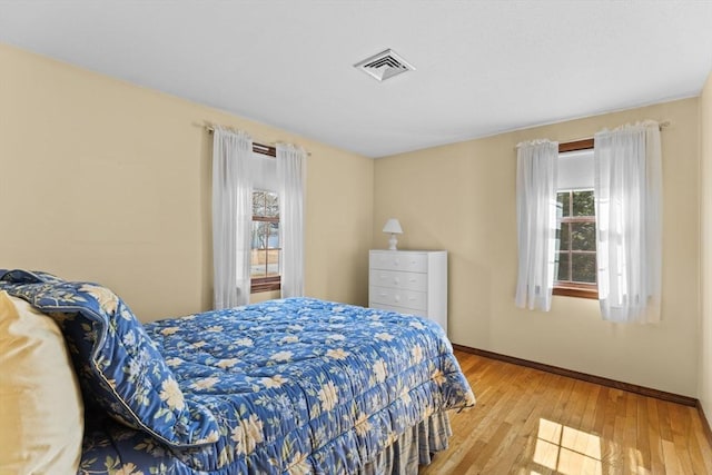 bedroom with hardwood / wood-style flooring, baseboards, and visible vents