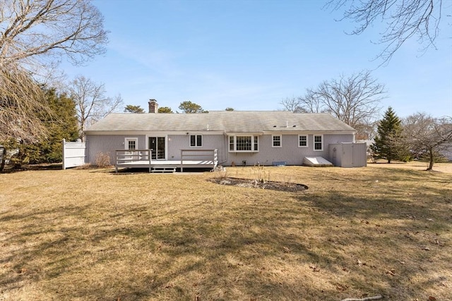 rear view of property with a lawn, a chimney, and a wooden deck