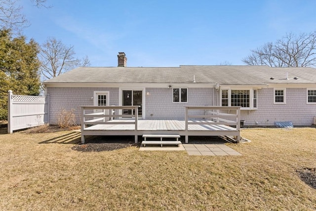 back of property featuring a deck, a yard, a chimney, and fence