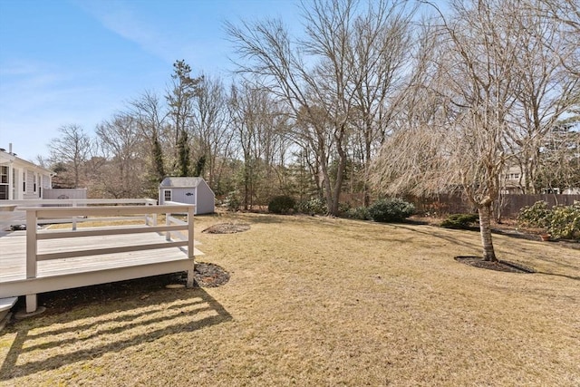 view of yard with a deck, a shed, an outdoor structure, and fence