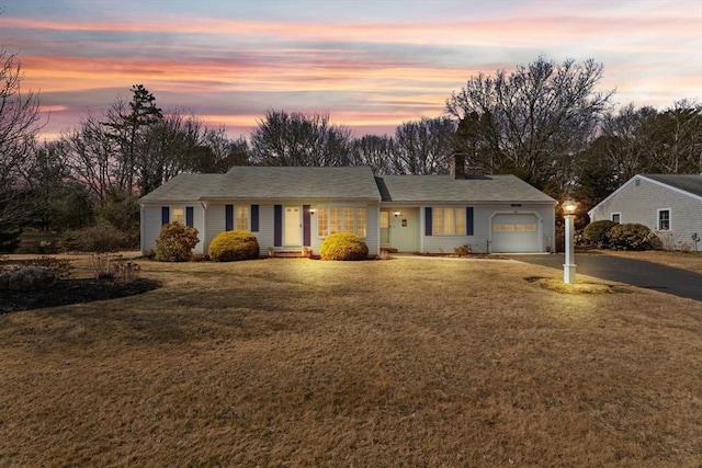 ranch-style house featuring a front lawn, driveway, and an attached garage