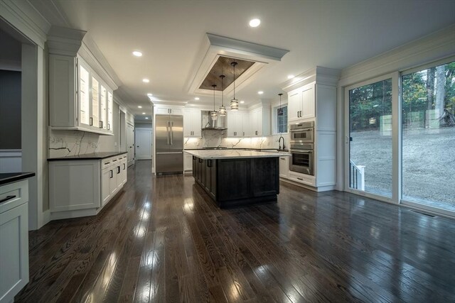 kitchen with a center island, appliances with stainless steel finishes, tasteful backsplash, decorative light fixtures, and white cabinetry