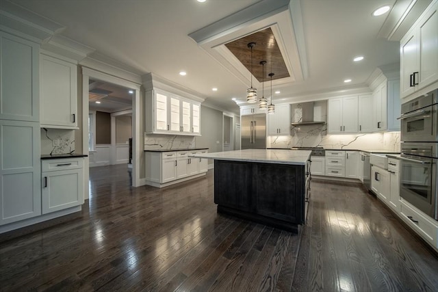 kitchen featuring pendant lighting, a center island, white cabinetry, and wall chimney exhaust hood