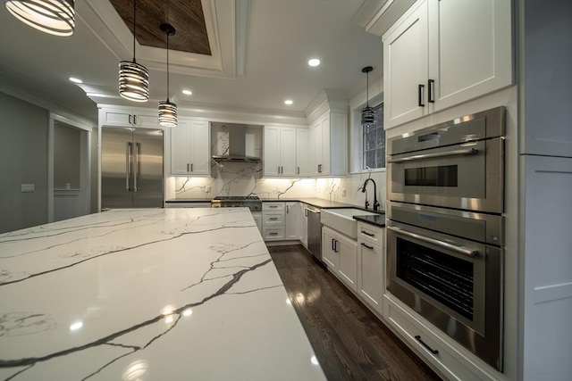 kitchen featuring sink, stainless steel appliances, wall chimney range hood, light stone counters, and white cabinets