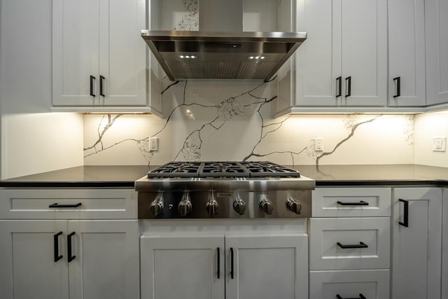 kitchen with stainless steel gas stovetop, wall chimney exhaust hood, white cabinets, and decorative backsplash