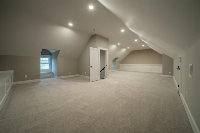 additional living space featuring light colored carpet and vaulted ceiling