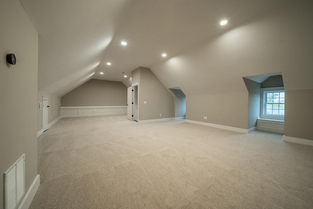 additional living space featuring light colored carpet and vaulted ceiling