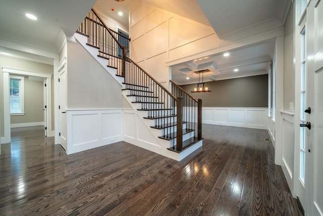 entryway with beam ceiling, coffered ceiling, dark hardwood / wood-style flooring, a notable chandelier, and ornamental molding