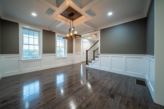 spare room with coffered ceiling, dark wood-type flooring, ornamental molding, and a notable chandelier