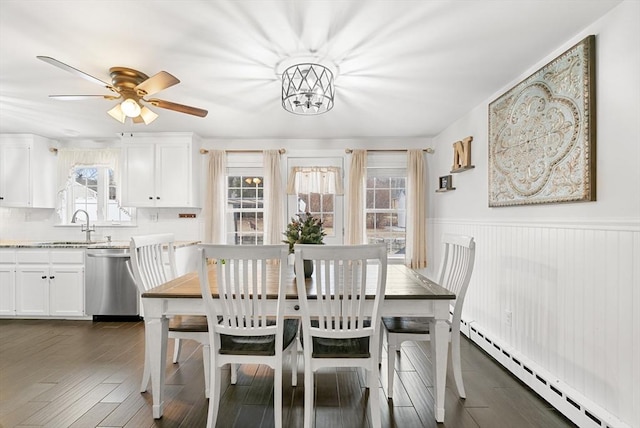 dining space featuring dark hardwood / wood-style flooring, ceiling fan, sink, and a baseboard radiator