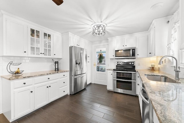 kitchen with tasteful backsplash, light stone counters, stainless steel appliances, sink, and white cabinets