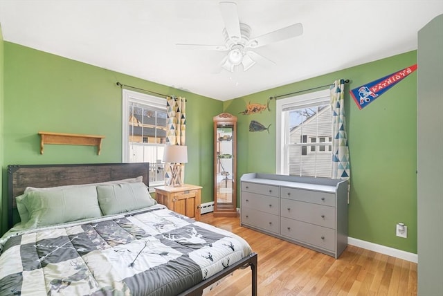 bedroom featuring multiple windows, light wood-type flooring, baseboard heating, and ceiling fan