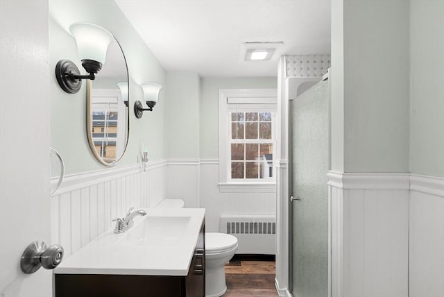 bathroom featuring hardwood / wood-style floors, vanity, a shower, toilet, and radiator heating unit