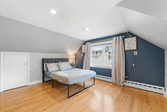 bedroom featuring baseboard heating, hardwood / wood-style floors, and lofted ceiling