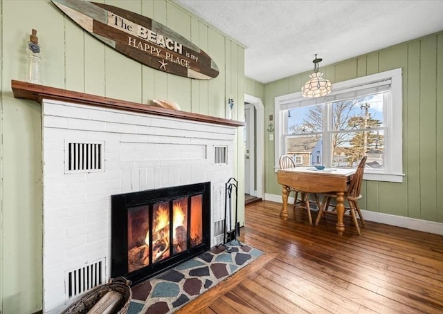 details with wood finished floors, visible vents, baseboards, a fireplace, and a textured ceiling