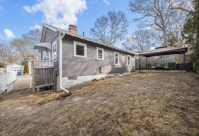 rear view of property with a gazebo, an outdoor hangout area, a chimney, and fence