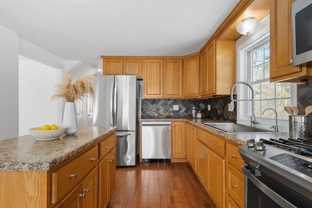 kitchen featuring appliances with stainless steel finishes, sink, backsplash, a center island, and dark hardwood / wood-style flooring