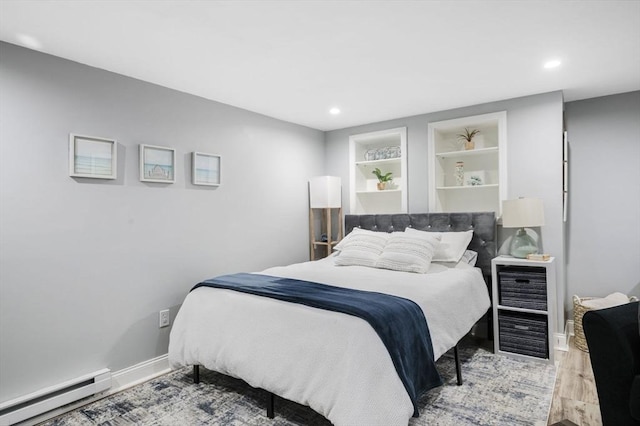 bedroom with hardwood / wood-style floors and a baseboard heating unit