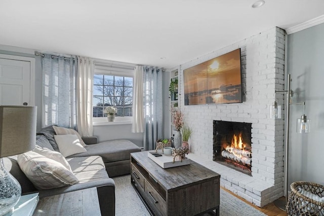 living room with light hardwood / wood-style flooring, a brick fireplace, and crown molding