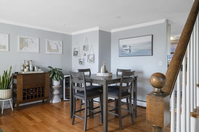 dining room with wood-type flooring, baseboard heating, and crown molding