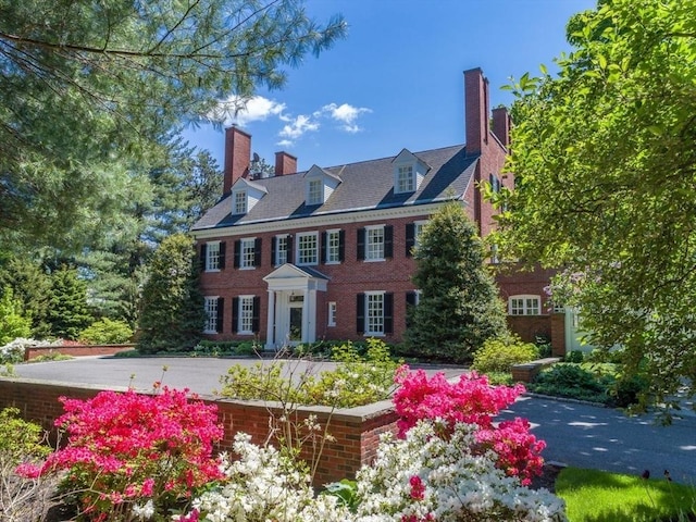 colonial inspired home featuring brick siding and a chimney