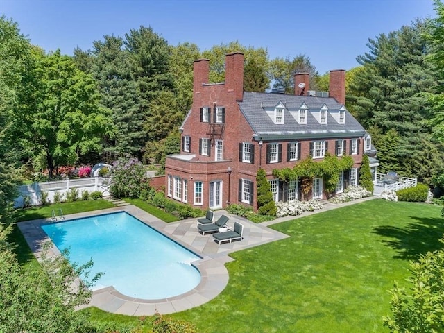 back of property featuring a fenced backyard, a yard, an outdoor pool, a chimney, and a patio area