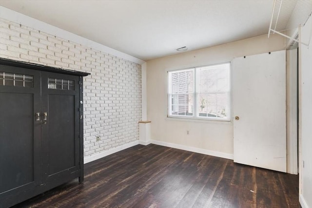 foyer featuring dark wood-type flooring and brick wall