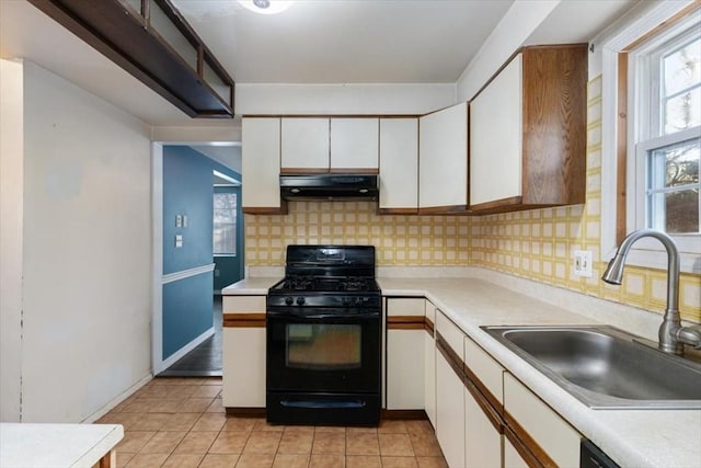 kitchen featuring black gas range, backsplash, white cabinets, sink, and extractor fan