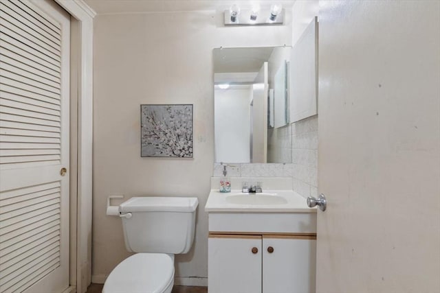 bathroom featuring vanity, backsplash, and toilet