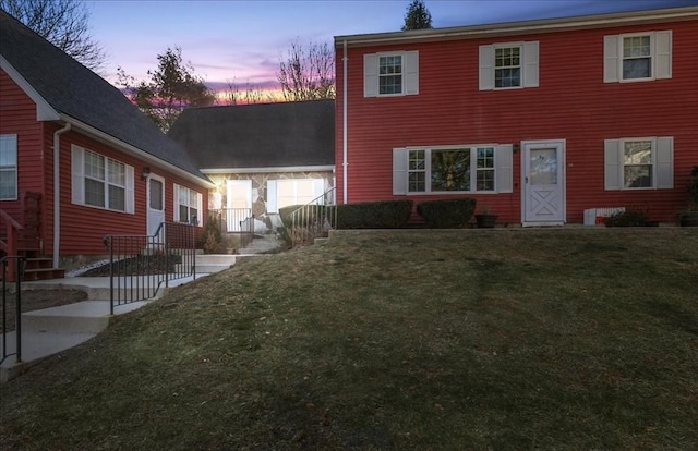 back house at dusk featuring a yard